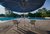 Sonnenschirm mit Stühlen vor Schwimmbecken