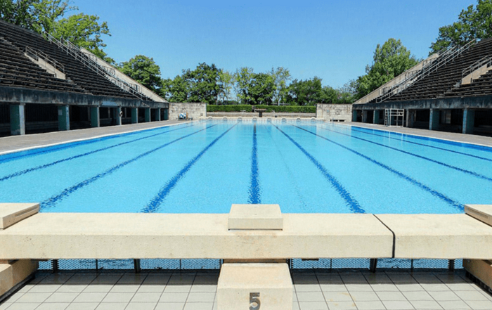 leeres Außenbecken mit Startblöcken und Zuschauertribünen