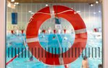 Ein orangener Rettungsring, durch den man ein Schwimmbad sieht