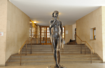 bronze Statue einer nackten Frau vor einer Treppe
