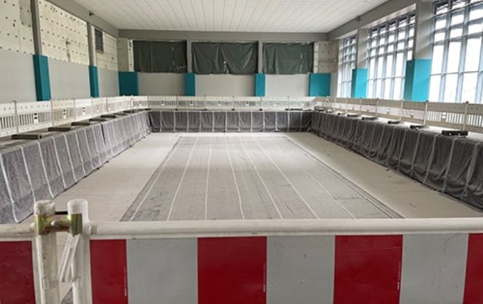 Blick auf das leere 25-Meter-Becken mit einem Absperrzaun davor