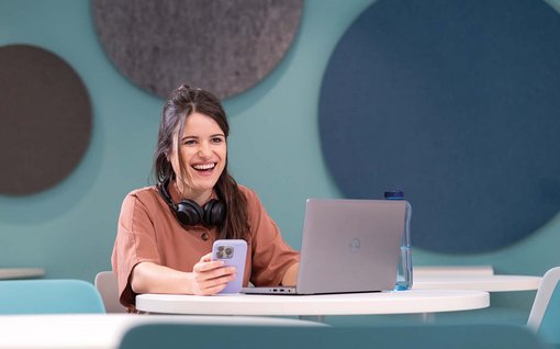 Lachende Frau vor einem Notebook in einem Büro